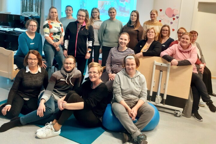 Ryhmäkuvassa ihmisiä seinälle heijastetun kuvan edessä.
